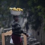 A street vendor walks with her merchandise on her head in Port-au-Prince, Haiti, Sunday, Oct. 17, 2021. A group of 17 U.S. missionaries including children was kidnapped by a gang in Haiti on Saturday, Oct. 16, according to a voice message sent to various religious missions by an organization with direct knowledge of the incident. (AP Photo/Joseph Odelyn)