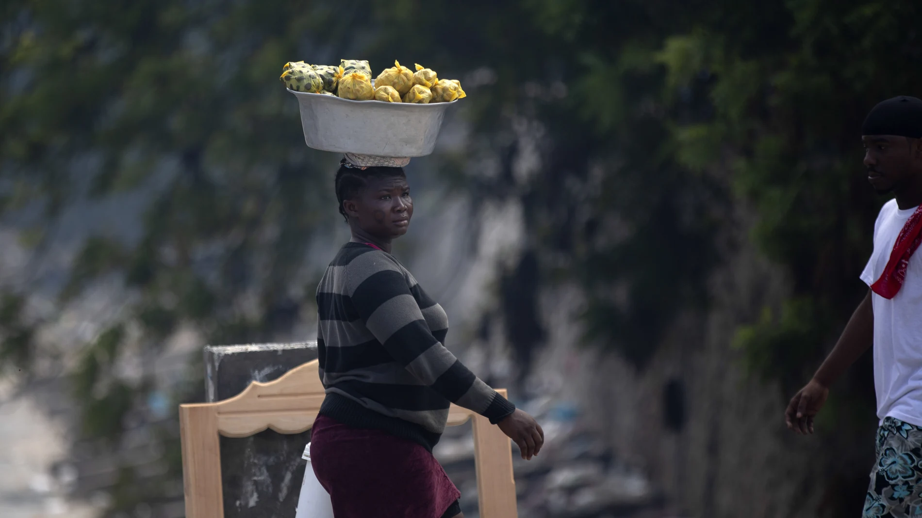 A street vendor walks with her merchandise on her head in Port-au-Prince, Haiti, Sunday, Oct. 17, 2021. A group of 17 U.S. missionaries including children was kidnapped by a gang in Haiti on Saturday, Oct. 16, according to a voice message sent to various religious missions by an organization with direct knowledge of the incident. (AP Photo/Joseph Odelyn)