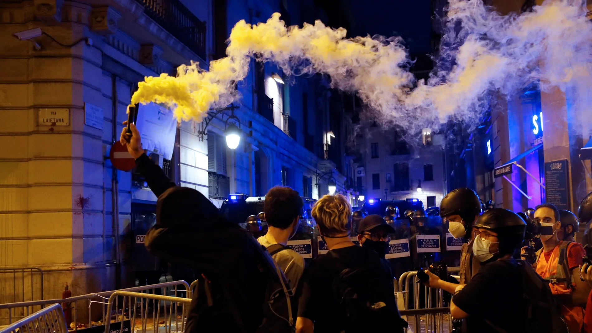 Manifestantes encienden bengalas frente a los agentes de los Mossos d'Esquadra durante los incidentes registrados en las inmediaciones de la comisaría de Vía Lietana de Barcelona, al finalizar la manifestación convocada por la ANC este sábado en Barcelona con motivo de la Diada del 11 de septiembre.