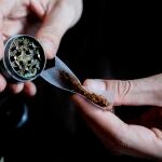 En la imagen, una persona se lía un cigarro con marihuana