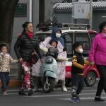 Residents, some wearing masks, cross a road in Beijing, China, Wednesday, Oct. 20, 2021. China's capital Beijing has begun offering booster shots against COVID-19, four months before the city and surrounding regions are to host the Winter Olympics. (AP Photo/Ng Han Guan)