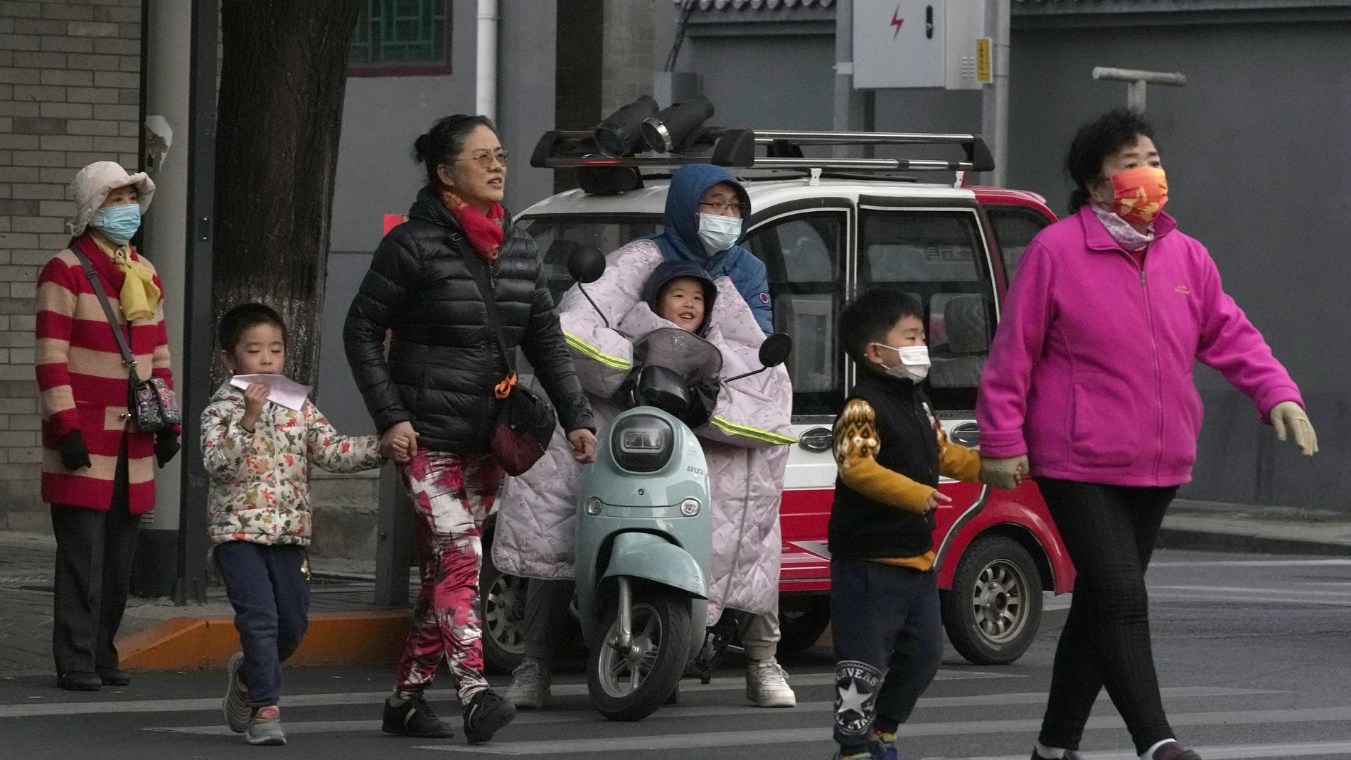 Residents, some wearing masks, cross a road in Beijing, China, Wednesday, Oct. 20, 2021. China's capital Beijing has begun offering booster shots against COVID-19, four months before the city and surrounding regions are to host the Winter Olympics. (AP Photo/Ng Han Guan)