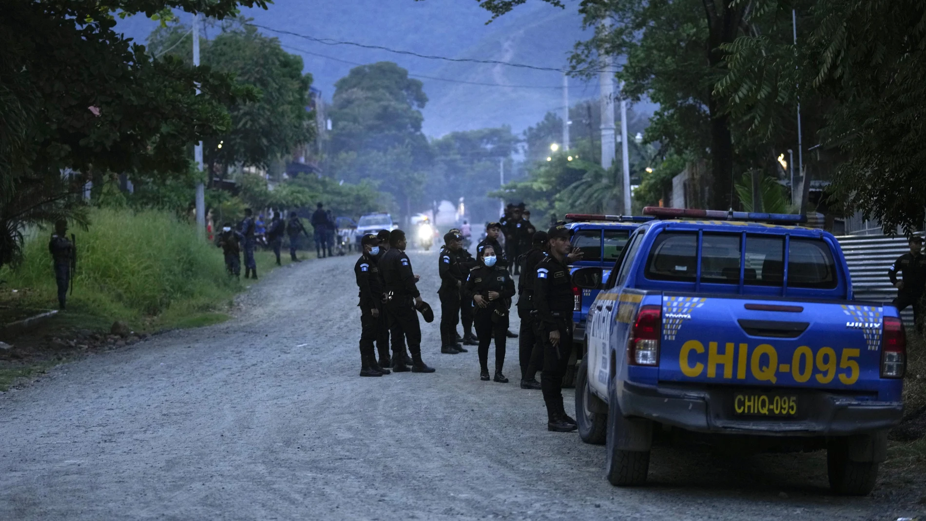 Police agents stand around a perimeter during raids in El Estor, at the northern coastal province of Izabal, Guatemala, Sunday, Oct. 24, 2021. The Guatemalan government has declared a month-long, dawn-to-dusk curfew and banned pubic gatherings following two days of protests against a mining project. (AP Photo/Moises Castillo)