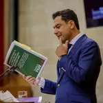 El presidente de la Junta , Juanma Moreno, sostiene el documento de las propuestas del PSOE. EFE/Julio Muñoz
