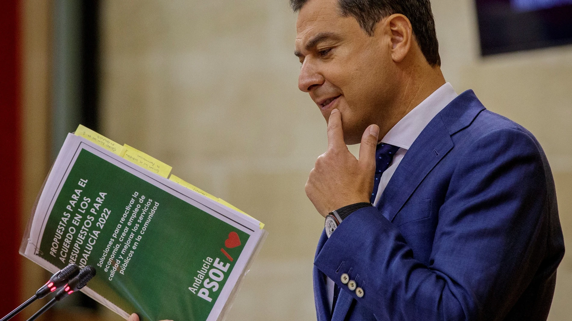 El presidente de la Junta , Juanma Moreno, sostiene el documento de las propuestas del PSOE. EFE/Julio Muñoz