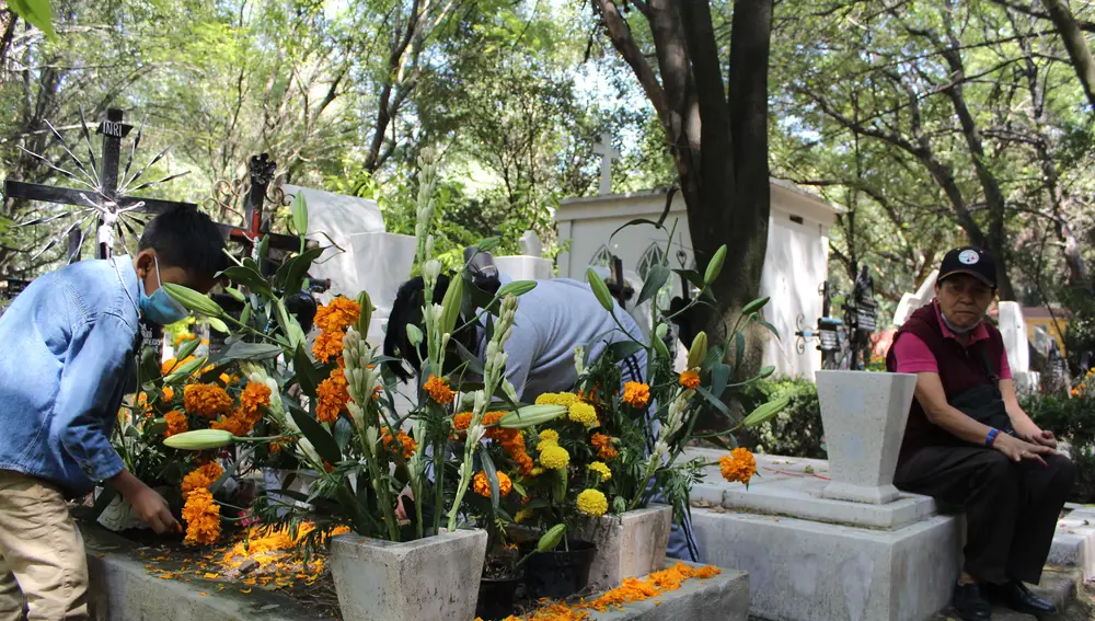 Germán Capultitla y hermana colocan con mimo las últimas flores junto a la piruleta y el chicle en recuerdo de sus tía María Guadalupe y su abuela Flora “porque les gustaban mucho”.