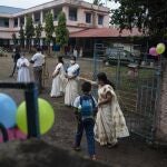 Una profesora guía a una estudiante para entrar en la escuela el día en el que se reabren despues de 20 meses cerradas. En Kochi, en el estado de Kerala (India), a 1 de noviembre de 2021