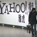 Una mujer pasa junto a un anuncio de Yahoo en el metro de Pekín