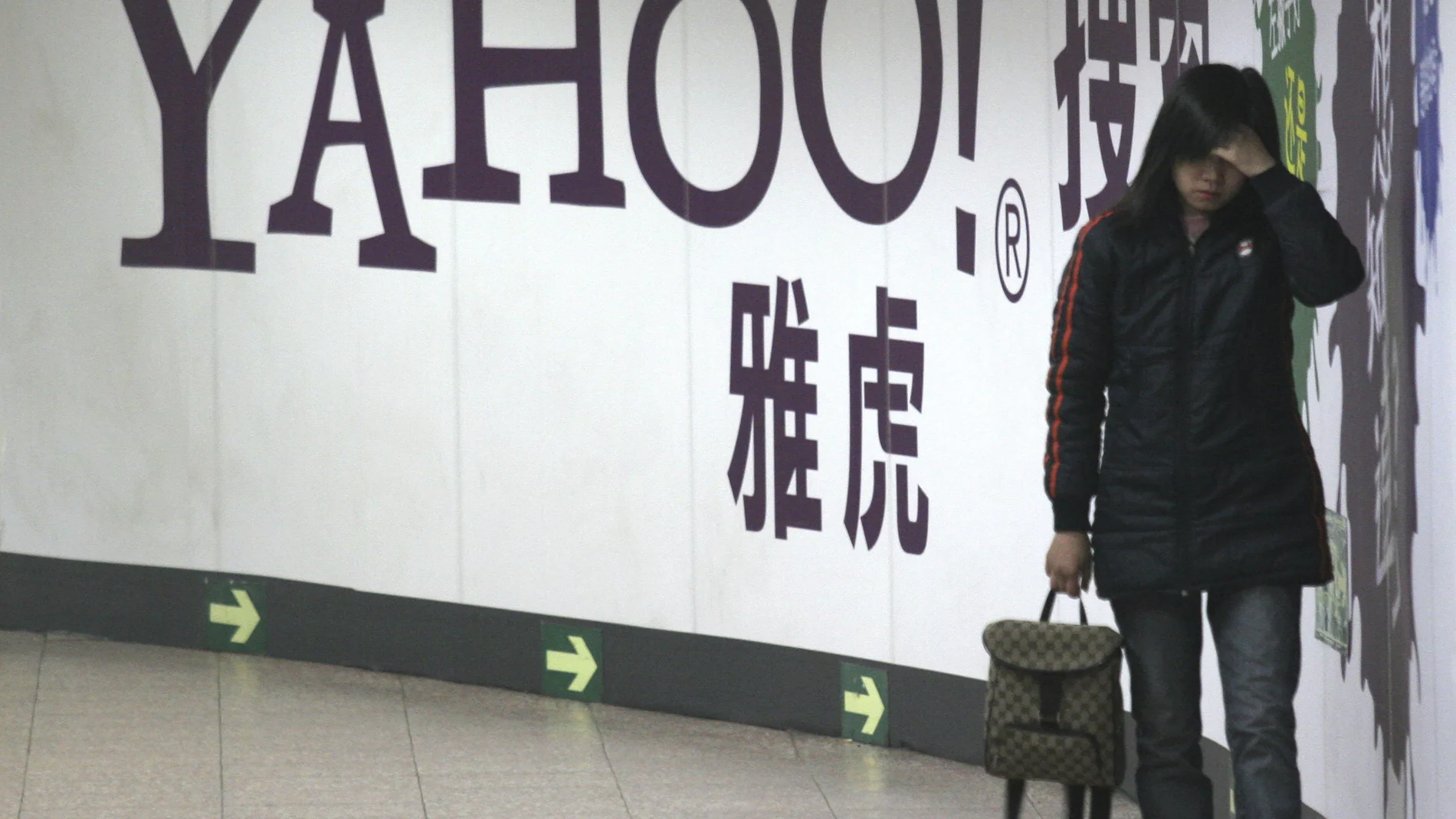 Una mujer pasa junto a un anuncio de Yahoo en el metro de Pekín