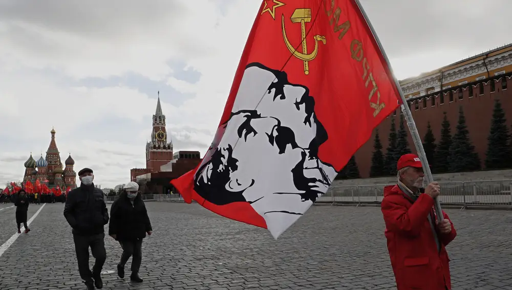 Un partidario del partido comunista ruso sostiene una bandera con retratos de los líderes comunistas Stalin y Lenin después de la ceremonia de colocación de flores en el mausoleo de Lenin (Rusia, Moscú) EFE/EPA/MAXIM SHIPENKOV