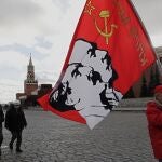Un partidario del partido comunista ruso sostiene una bandera con retratos de los líderes comunistas Stalin y Lenin después de la ceremonia de colocación de flores en el mausoleo de Lenin (Rusia, Moscú) EFE/EPA/MAXIM SHIPENKOV