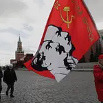 Un partidario del partido comunista ruso sostiene una bandera con retratos de los líderes comunistas Stalin y Lenin después de la ceremonia de colocación de flores en el mausoleo de Lenin (Rusia, Moscú) EFE/EPA/MAXIM SHIPENKOV