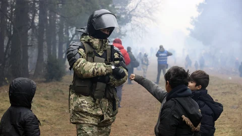 Un soldado de Bielorrusia con niños refugiados en la frontera con Polonia