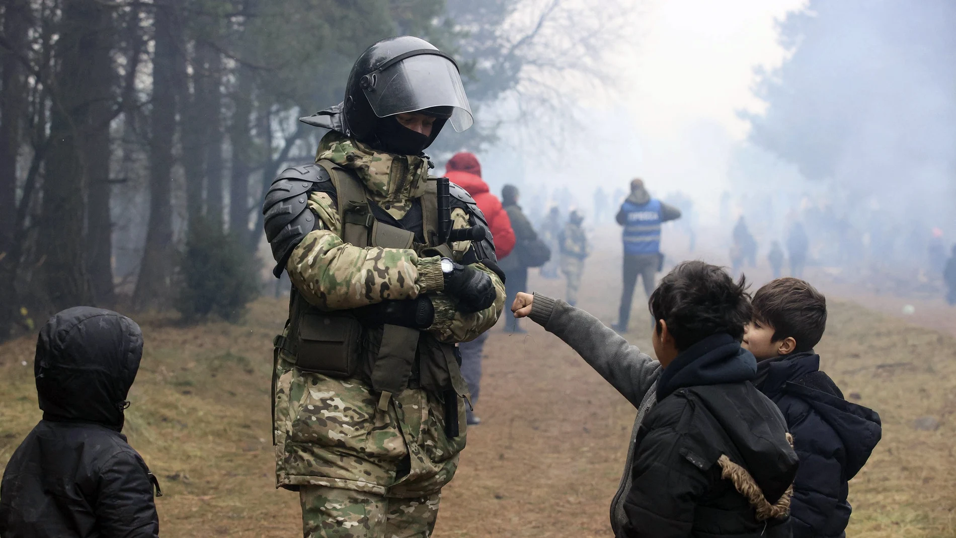 Un soldado de Bielorrusia con niños refugiados en la frontera con Polonia