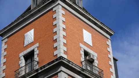 Dos de los escudos franquistas, antes de su retiro, tapados con lonas