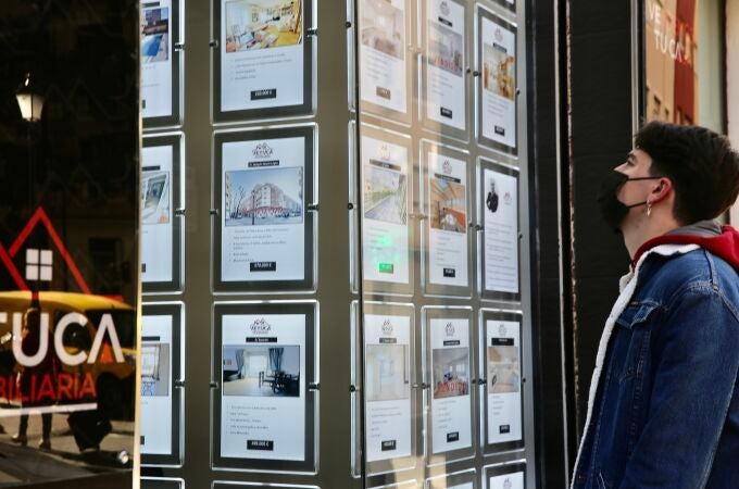 Un joven observa carteles de viviendas en venta y alquiler