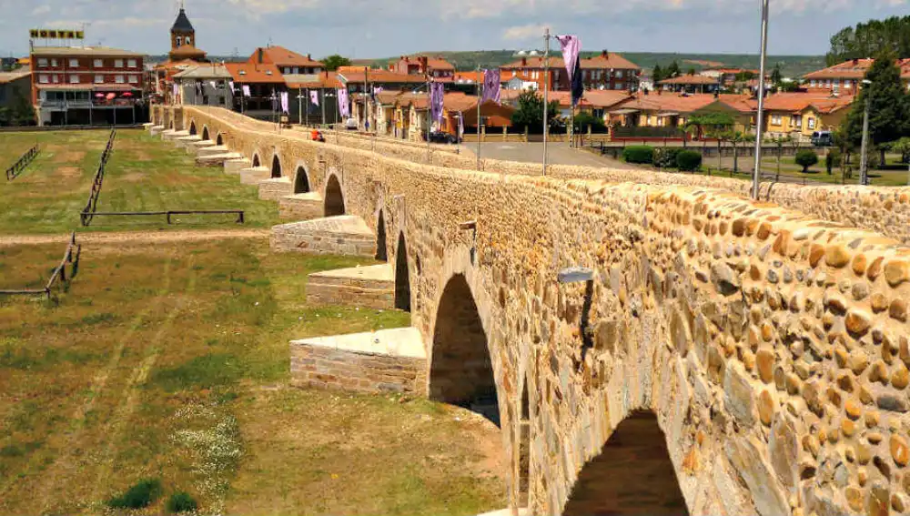 Puente medieval y al fondo la parroquia de Hospital del Río Órbigo (León)