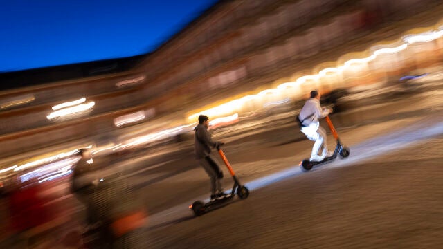 Imagen nocturna de tres patinetes eléctricos por la Plaza Mayor