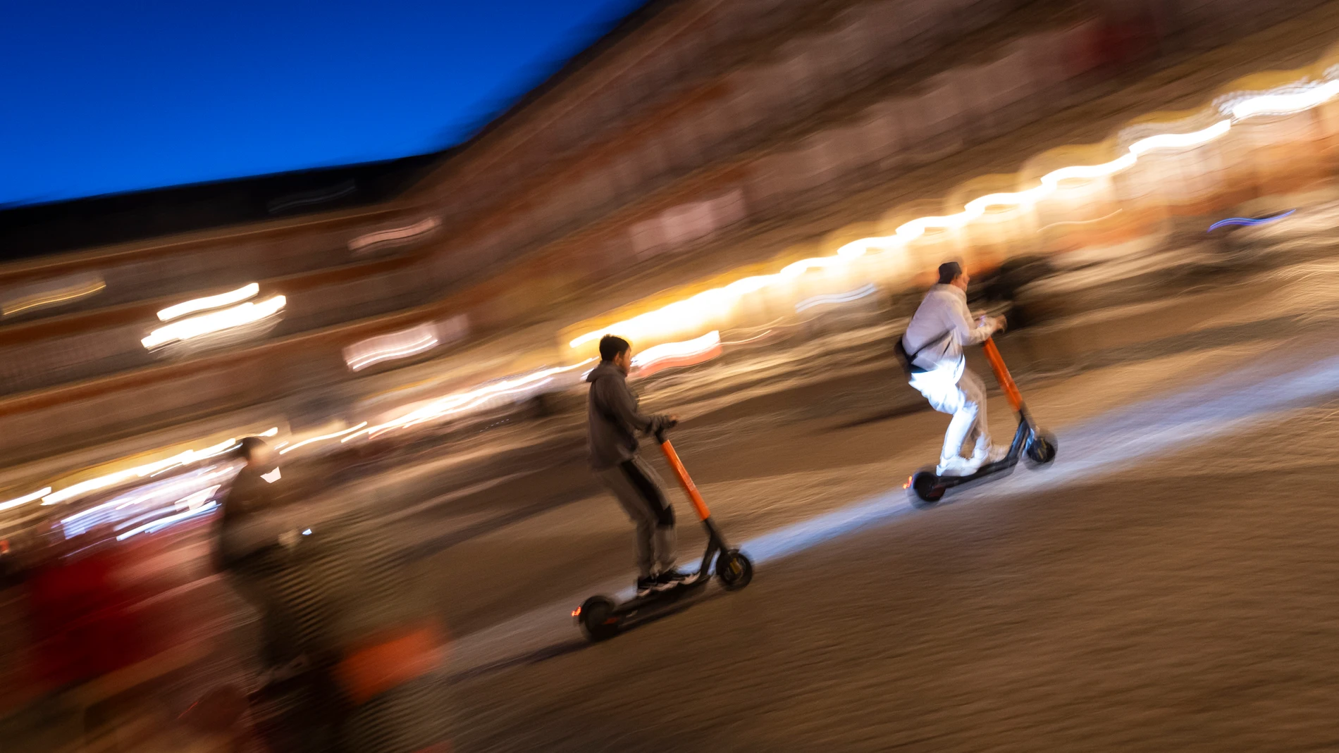 Imagen nocturna de tres patinetes eléctricos por la Plaza Mayor