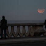 Tres personas observan un eclipse lunar parcial desde A Coruña