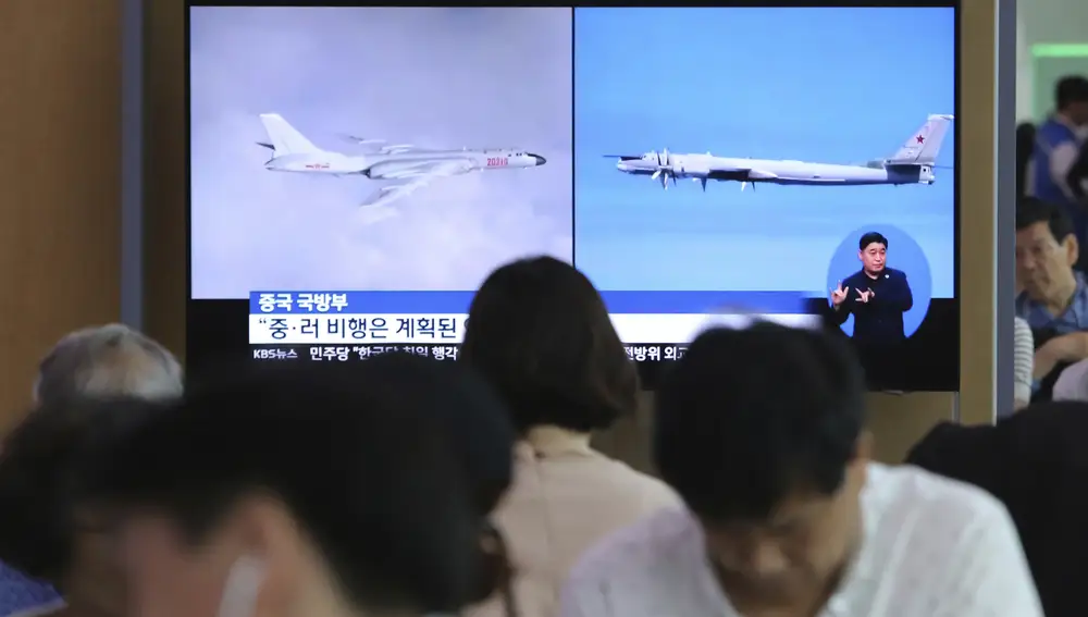 Varias personas en Corea del Sur junto a una televisión con imágenes del bombardero ruso Tu-95 y del bombardero chino H-6 que ingresaron en la zona de defensa aérea de Seúl sin previo aviso.