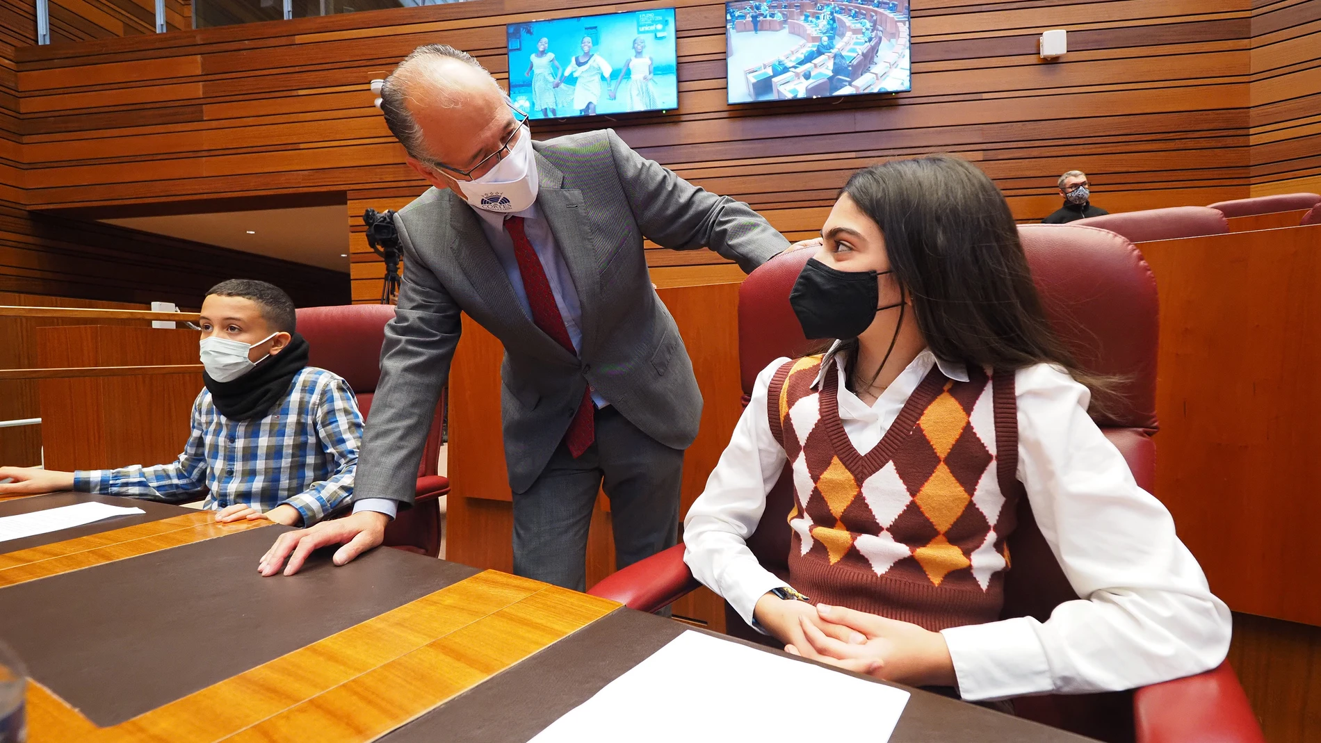 El presidente de las Cortes de Castilla y León, Luis Fuentes, conversa con dos de los niños participantes en el Pleno