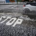 Un coche circula por la carretera cubierta de granizo