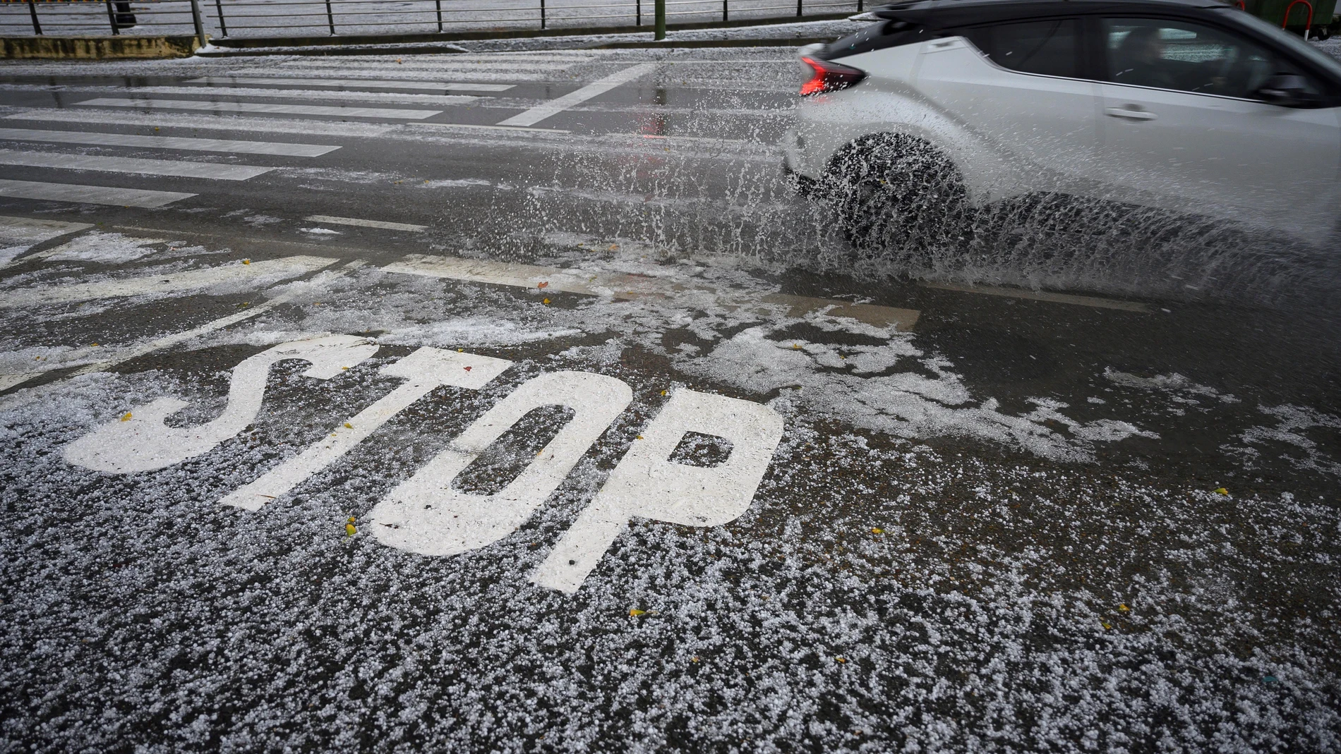Un coche circula por la carretera cubierta de granizo
