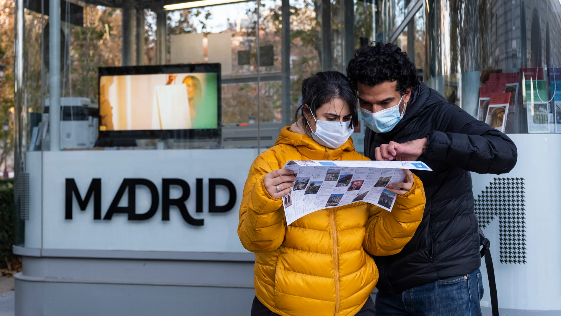 Una pareja de turistas consultando un mapa de Madrid junto a una oficina de información turística en Plaza de Oriente