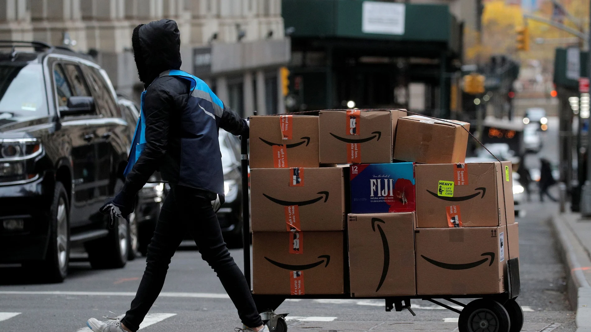 An Amazon delivery worker pulls a cart full of boxes for delivery on Cyber-Monday in New York City, U.S., November 29, 2021. REUTERS/Brendan McDermid REFILE - CORRECTING DATE