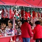 Varias personas visitan un puesto de venta de artículos de Navidad en la Plaza Mayor de Madrid