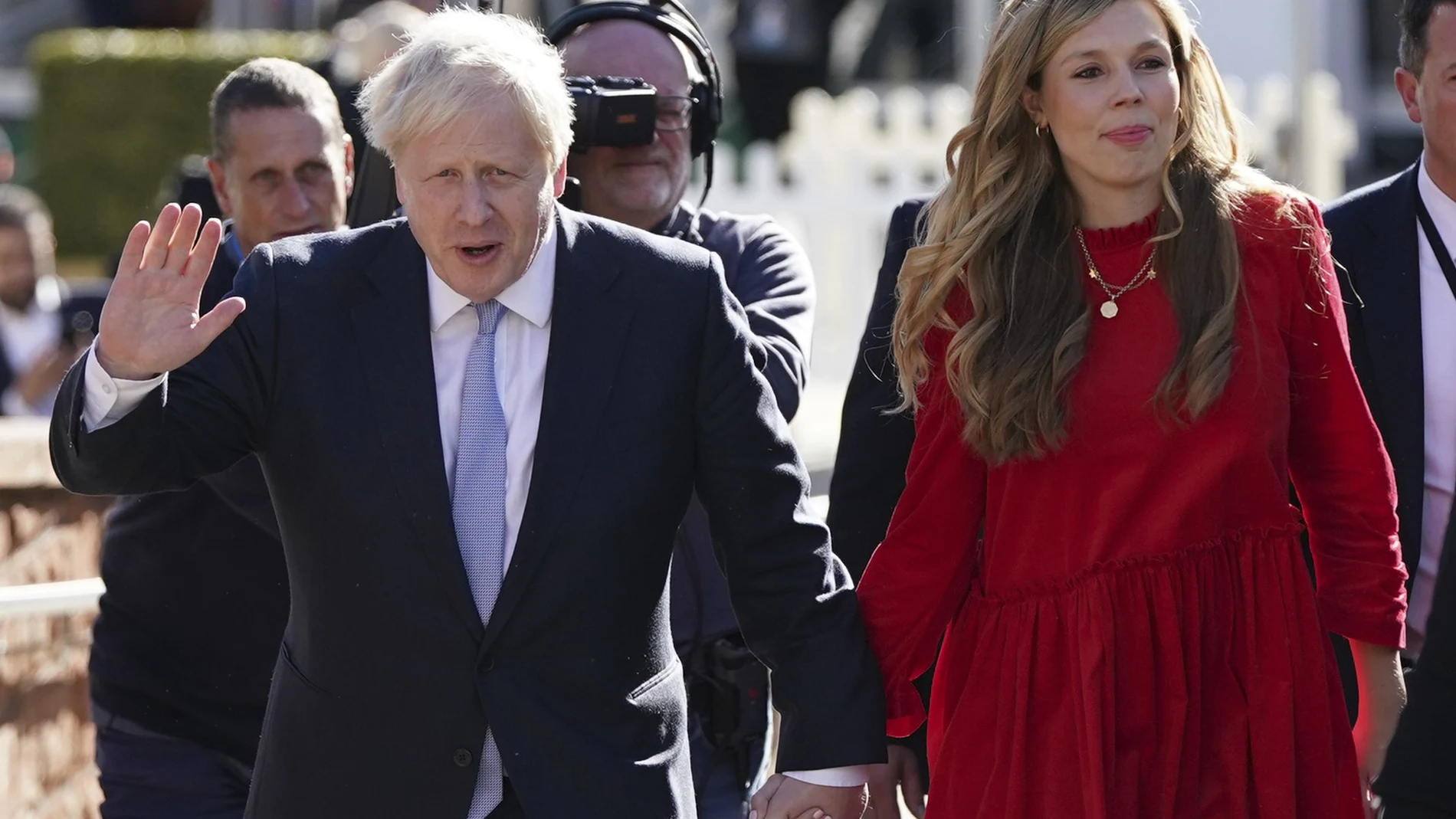 Johnson saluda a los medios mientras camina junto a su esposa Carrie antes de dar su discurso de apertura en la conferencia del Partido Conservador en Manchester