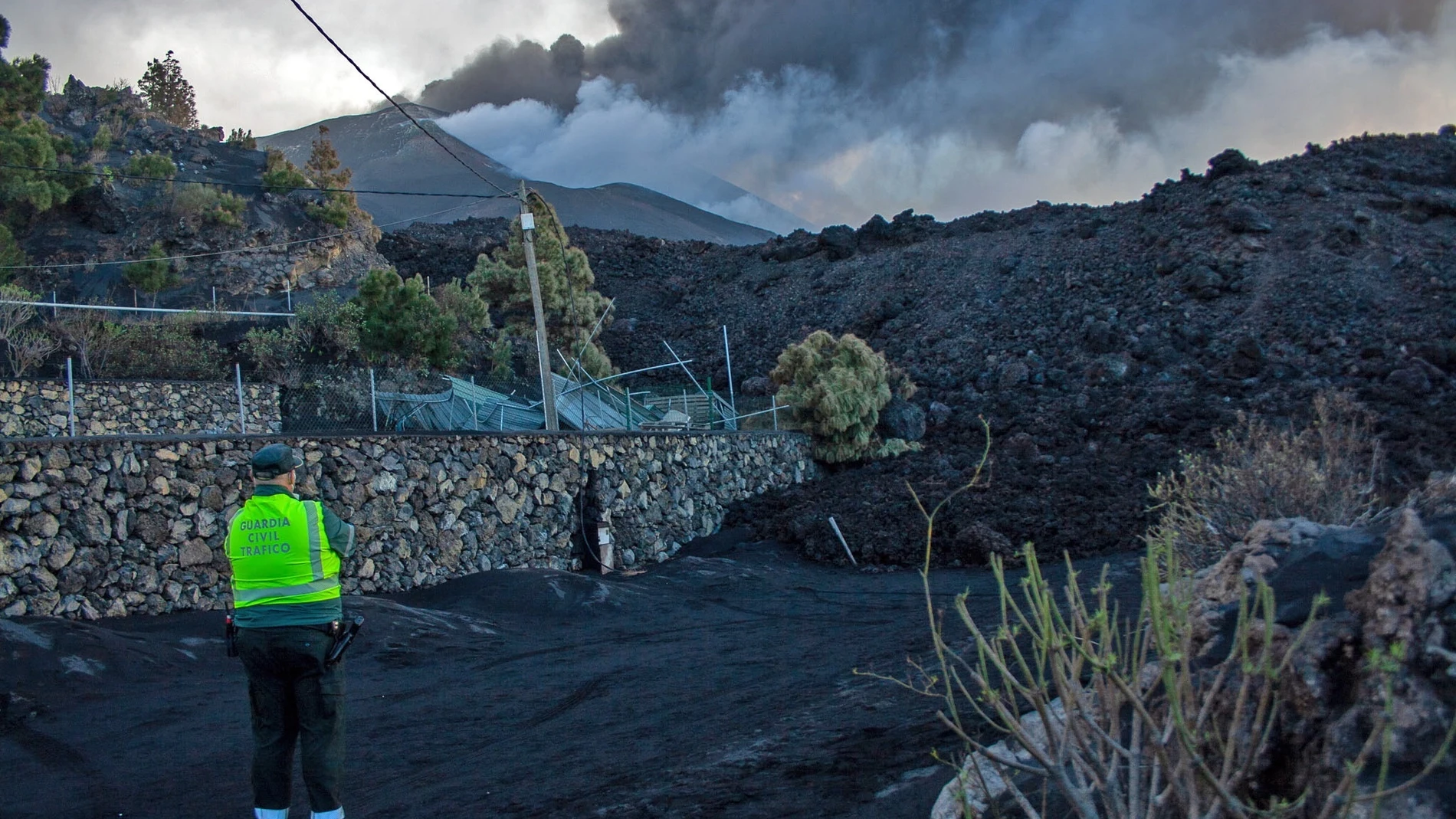 Un agente de la Guardia Civil observa la última colada del volcán de Cumbre Vieja en el camino de Tacande