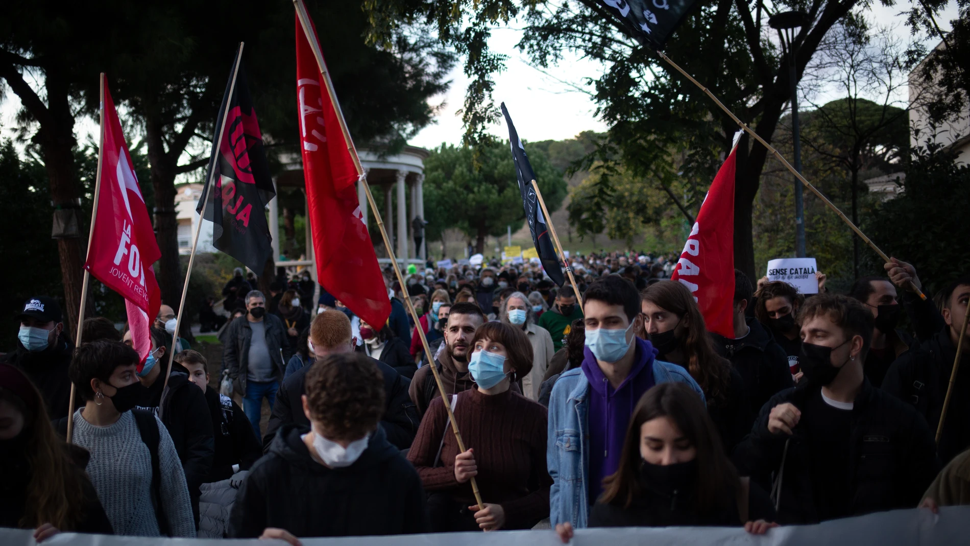 Varias personas con carteles participan en una manifestación contra el establecimiento de un 25% de castellano en las escuelas catalanas, frente a la escuela Turó del Drac