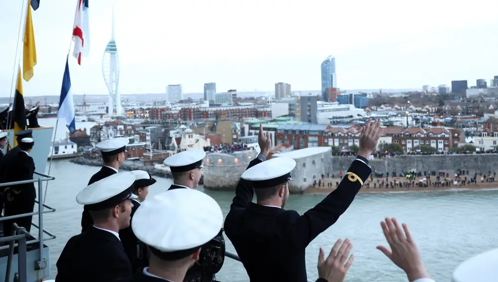 Miembros de la Marina británica saludan a su llegada al puerto de Portsmouth tras siete meses de travesía
