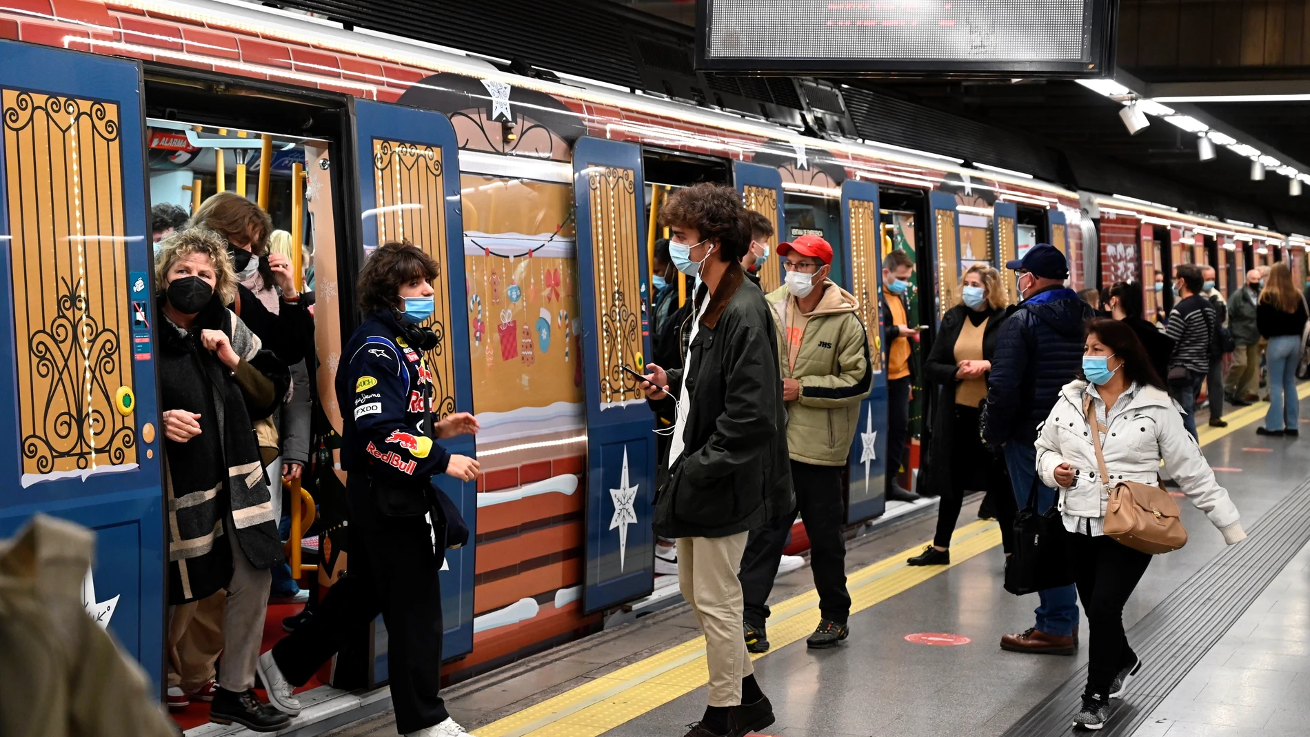 MADRID, 13/12/2021.- Varias personas hacen uso del tren de la línea 6 de metro de Madrid decorado con motivos navideños. EFE/ Fernando Villar