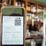 Detalle de un certificado covid en un smartphone, en una cafetería