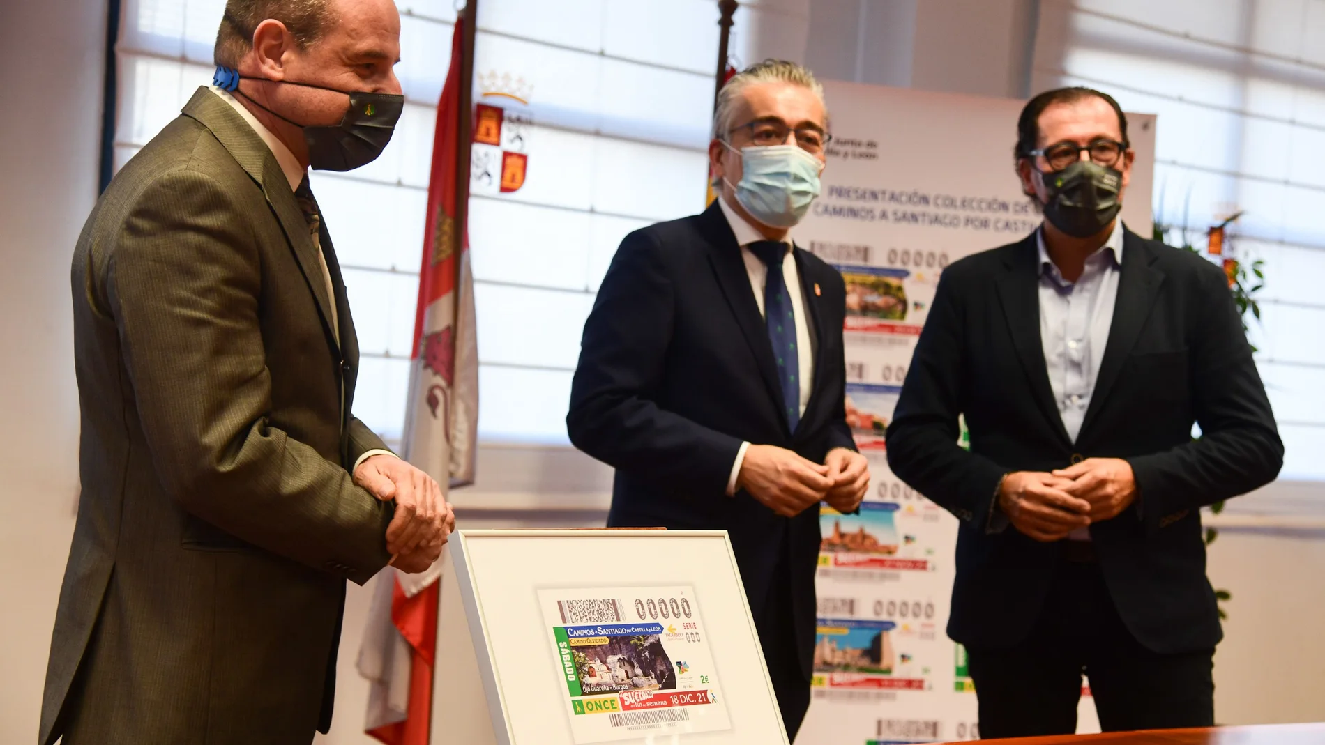 El delegado territorial de la Junta de Castilla y LeÓn en Burgos, Roberto Saiz; el delegado territorial de la ONCE en Castilla y LeÓn, Ismael PÉrez Blanco; y el director de ONCE en Burgos, Enrique Fernández Ortega, presentan el cupón que dedica al Camino Olvidado con una fotografía del Monumento Natural de Ojo Guareña (Burgos)