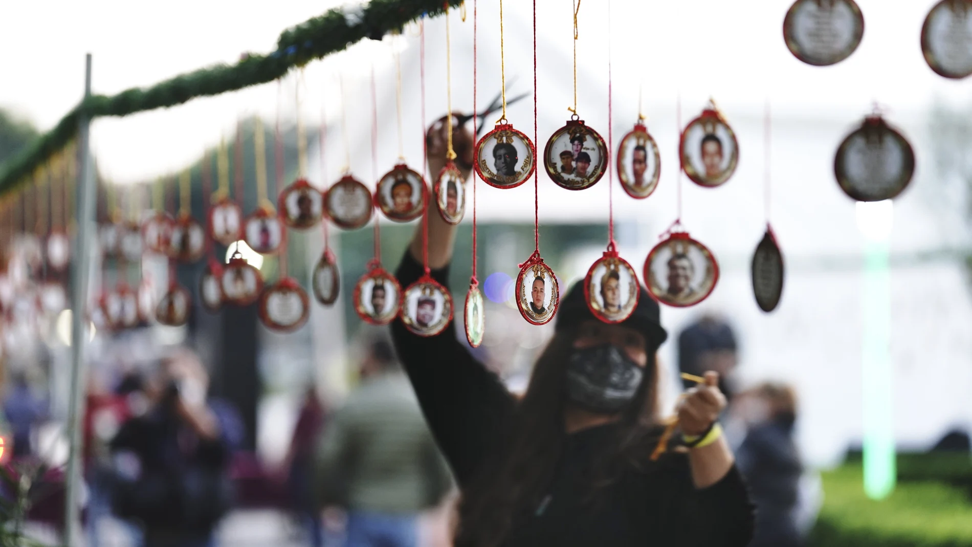 Relatives place Christmas decorations with images of their missing loved ones at the Memorial Garden of the City Government building of the borough of Iztacalco, in Mexico City, Tuesday, Dec. 14, 2021. (AP Photo/Marco Ugarte)