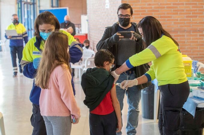Una enfermera de Servicio Murciano de Salud administra la vacuna de la covid a un niño acompañado, este miércoles en el Palacio de los Deportes de Murcia