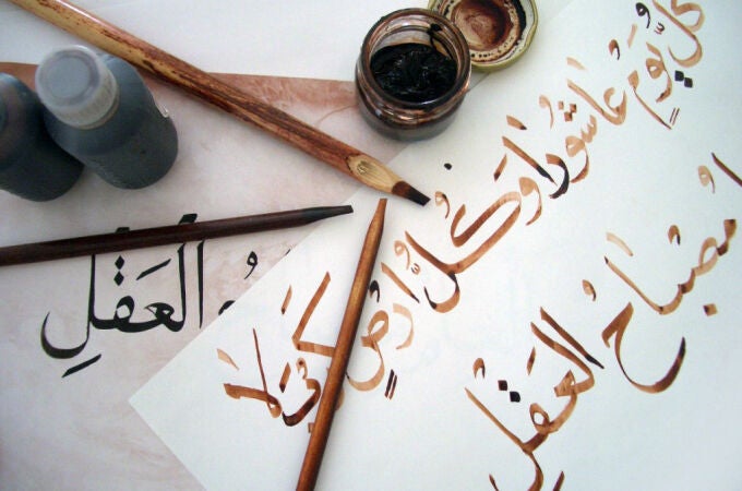 Obra de un estudiante de caligrafía árabe, utilizando bolígrafos de bambú y tinta marrón, trazando sobre la obra del profesor con tinta negra.