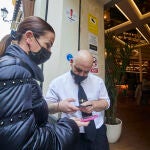 Un camarero escanea un certificado covid en la puerta de un bar