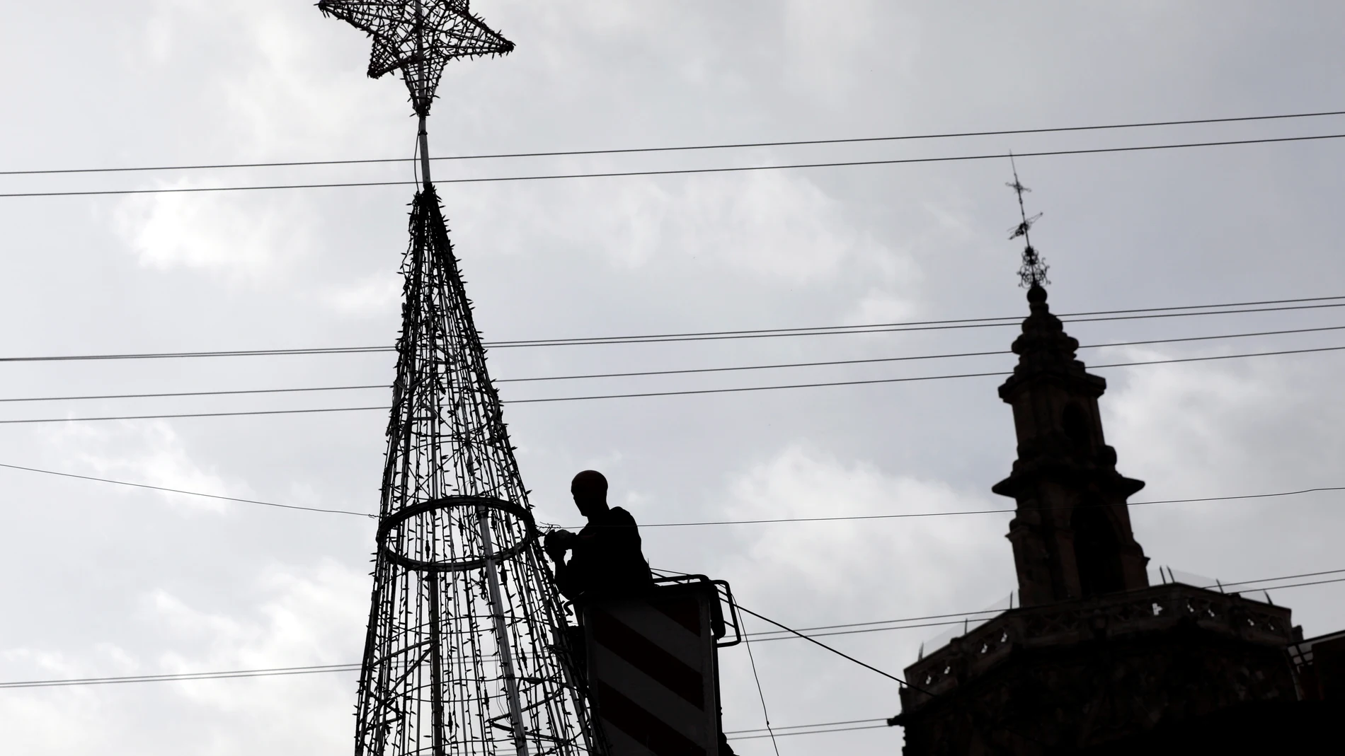 Un operario trabaja en un árbol de luces navideño en el casco antiguo de la ciudad en la que se respira ya el ambiente navideño