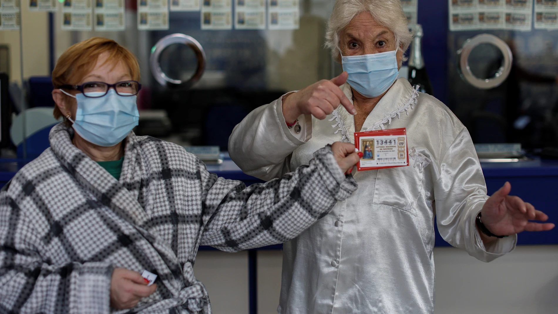 GRAFCVA1698. ALAQUÀS (VALENCIA), 21/12/2021.- Varias personas acuden a una administración de lotería de Alaquàs (Valencia), que regala décimos del sorteo de Navidad a los 50 primeros clientes que lleguen en pijama. EFE/Biel Aliño