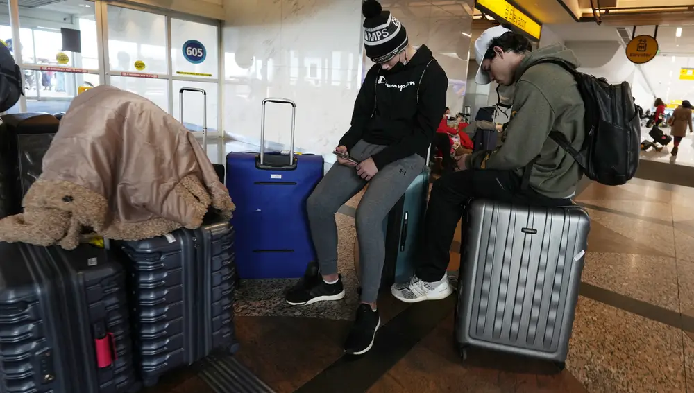 Los viajeros usan su equipaje como asientos cerca de las cintas transportadoras de equipaje de Southwest Airlines en el Aeropuerto Internacional de Denver. Las aerolíneas cancelaron cientos de vuelos el domingo, citando problemas de personal relacionados con la covid