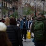 Viandantes caminan con bolsas por una vía de Barcelona.