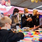 En la imagen, varias personas compran en mercadillos navideños