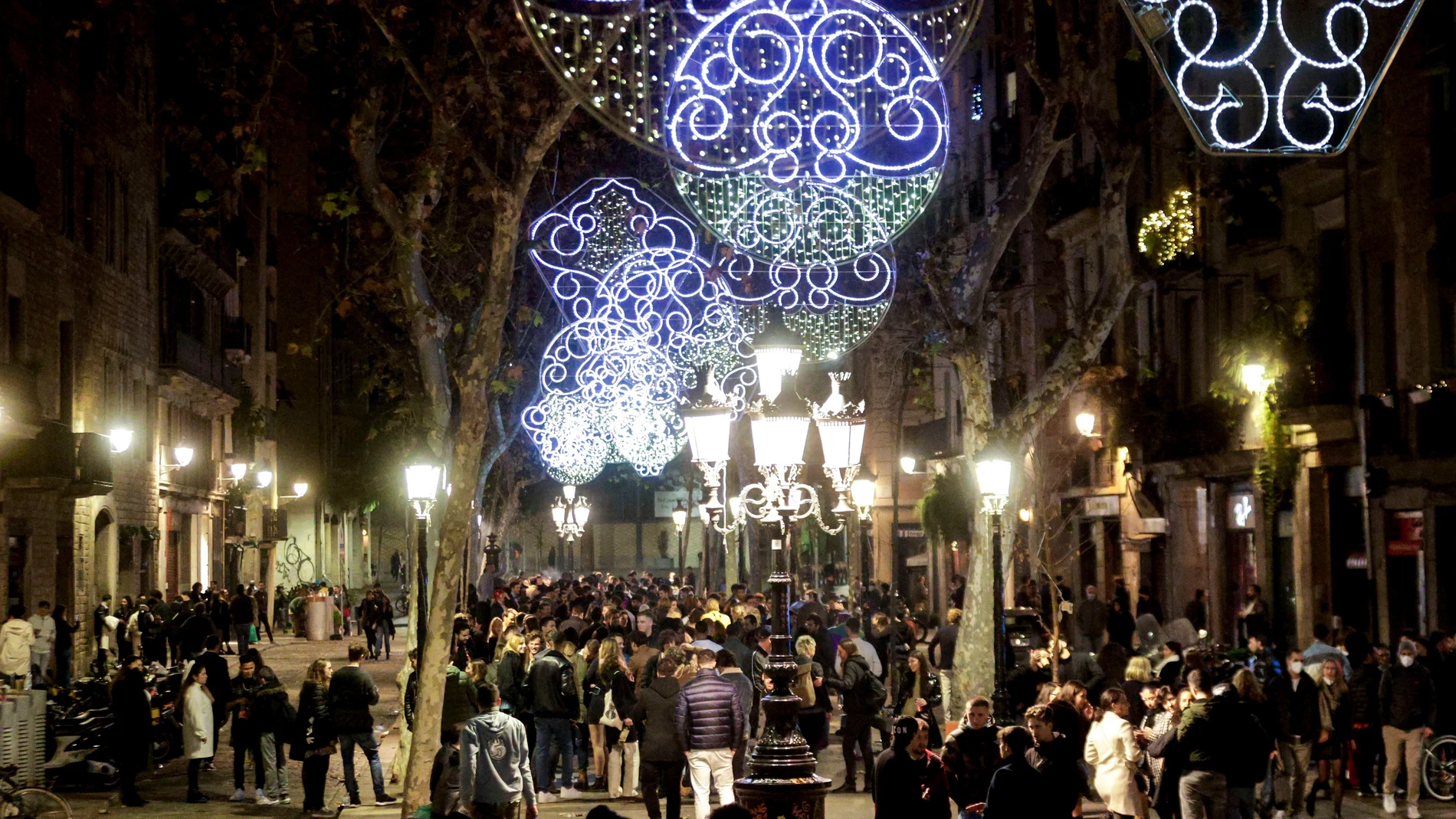 Varias personas celebran la entrada de año nuevo en el paseo de la Barceloneta de Barcelona, justo al inicio del horario del toque de queda a la una de la madrugada