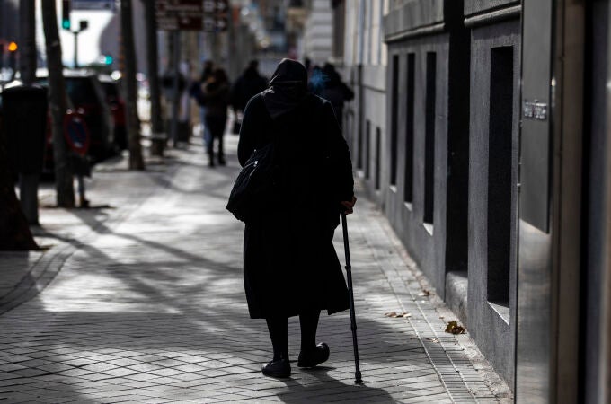 Una mujer de la tercera edad camina por una calle de Madrid