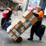 Un repartidor de mercancías con un carro lleno de cajas por el centro de Madrid